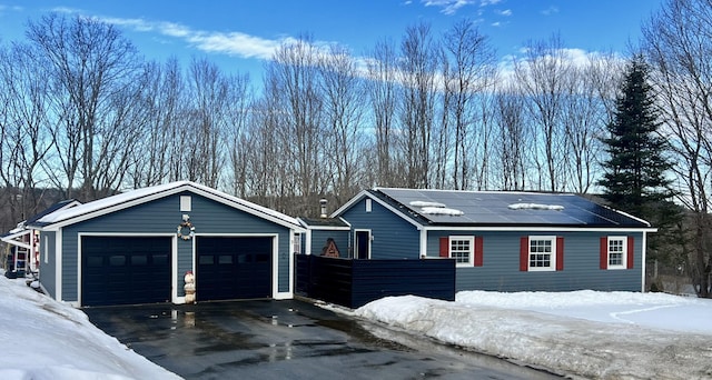 snow covered garage featuring a garage and solar panels