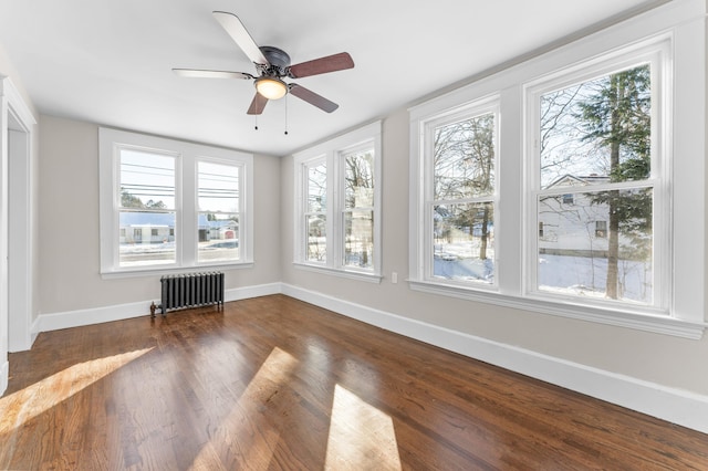 unfurnished sunroom with ceiling fan, radiator heating unit, and plenty of natural light