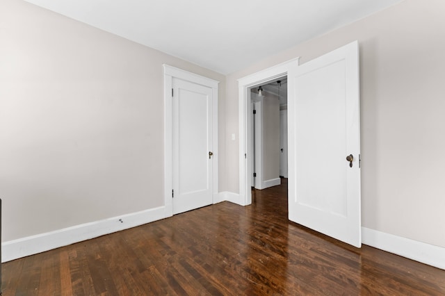 unfurnished bedroom with a closet and dark wood-type flooring