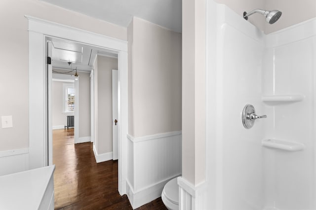 bathroom featuring hardwood / wood-style floors, toilet, walk in shower, and radiator