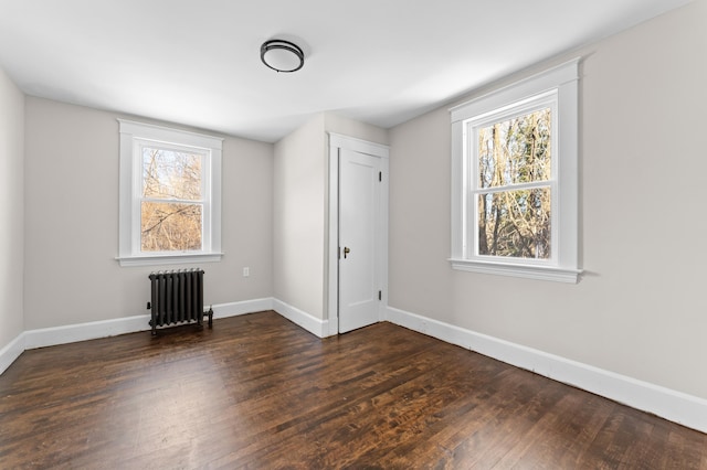 unfurnished room featuring dark hardwood / wood-style flooring and radiator heating unit