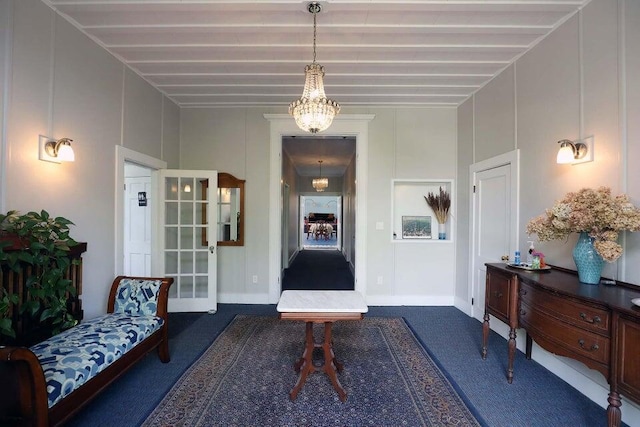 sitting room featuring beam ceiling, dark carpet, and a notable chandelier