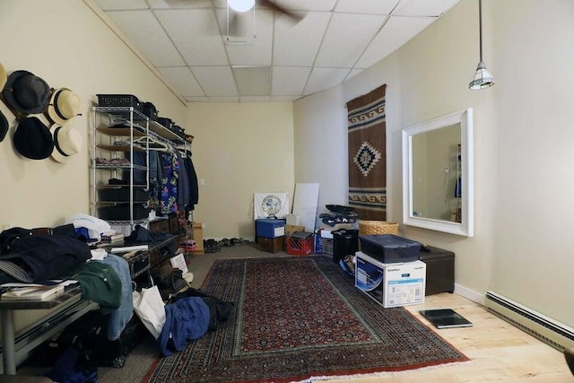 miscellaneous room featuring hardwood / wood-style flooring, a drop ceiling, ceiling fan, and a baseboard radiator