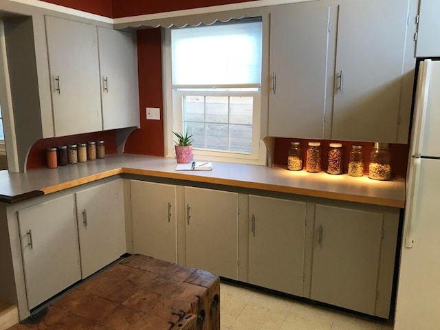 kitchen with white refrigerator and white cabinetry