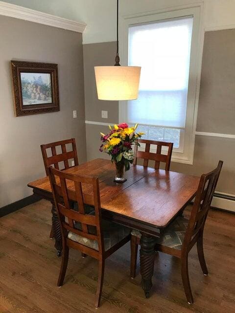 dining area with crown molding and dark wood-type flooring