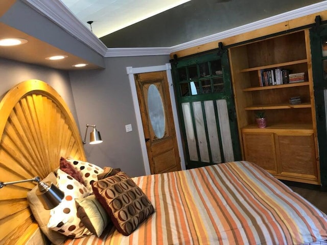 bedroom with a barn door, vaulted ceiling, and ornamental molding