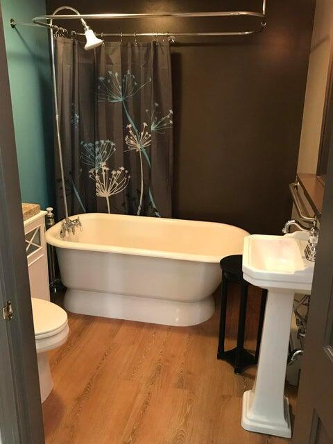 bathroom with hardwood / wood-style floors, a tub to relax in, toilet, and sink