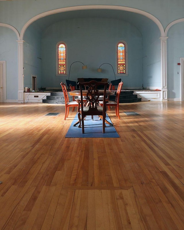 dining area featuring light wood-type flooring and decorative columns