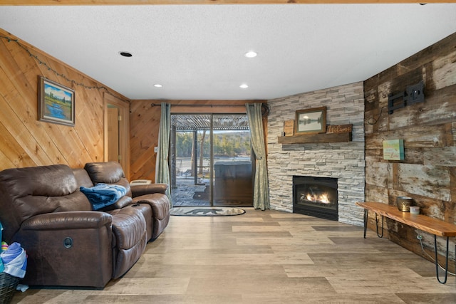 151 Mountain View Dr, Acton, ME 04001 - living room featuring wood walls, a fireplace, light hardwood / wood-style floors, and a textured ceiling