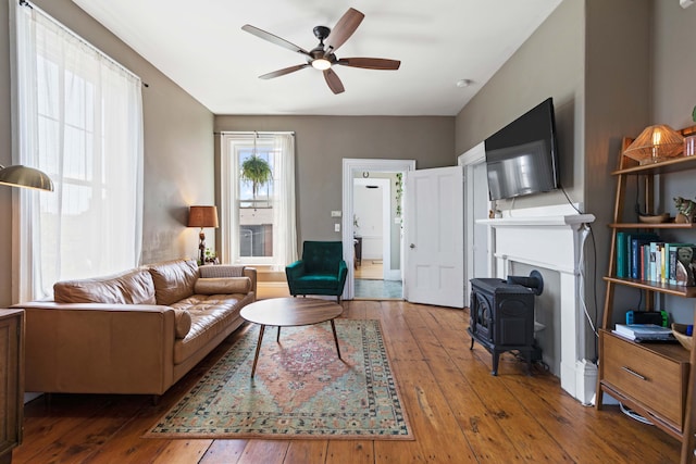 living room featuring hardwood / wood-style flooring, ceiling fan, and a wood stove