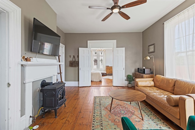 living room featuring a wood stove, ceiling fan, and hardwood / wood-style floors