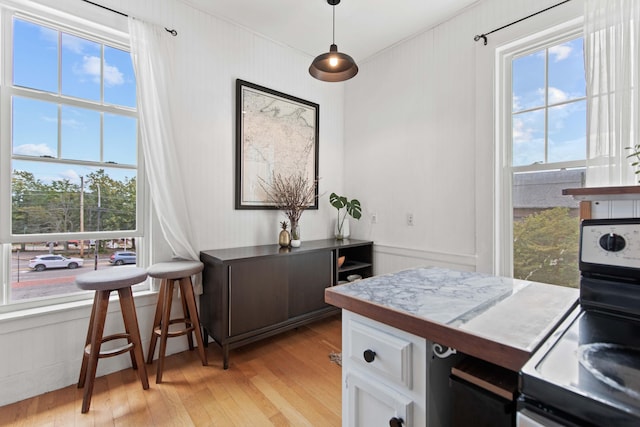 kitchen with plenty of natural light, white cabinetry, range, and light hardwood / wood-style flooring