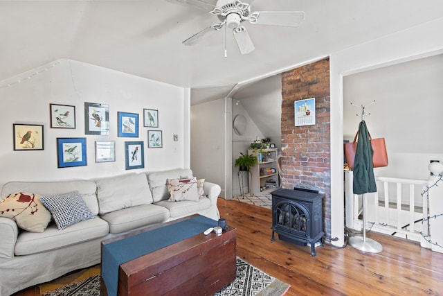 living room with hardwood / wood-style flooring, ceiling fan, a wood stove, and vaulted ceiling