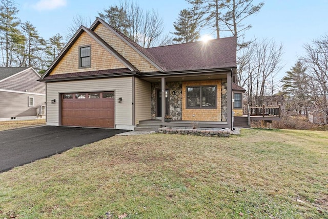 view of front of home with covered porch, a garage, and a front lawn