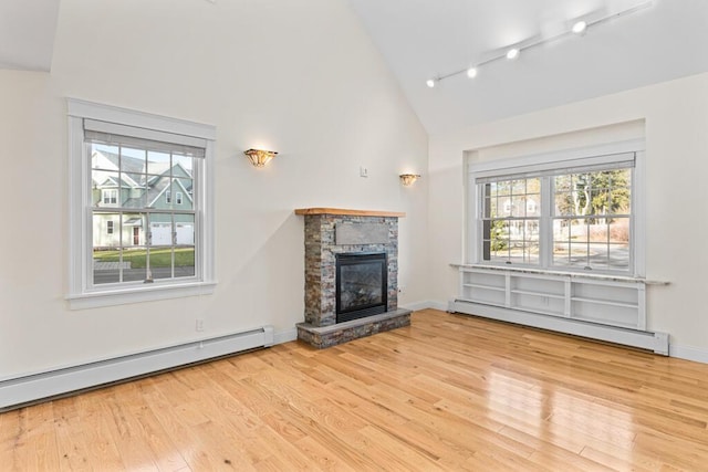 unfurnished living room featuring a fireplace, light hardwood / wood-style floors, track lighting, and a baseboard heating unit