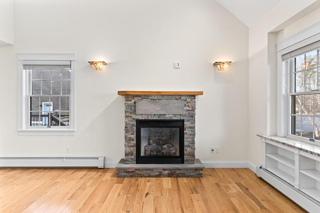 unfurnished living room featuring light wood-type flooring, a stone fireplace, baseboard heating, and lofted ceiling