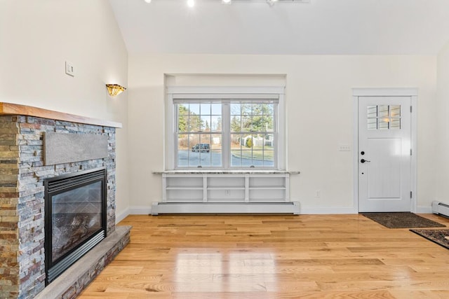 living room with a stone fireplace, light wood-type flooring, vaulted ceiling, and a baseboard heating unit