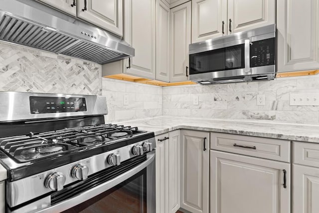 kitchen featuring tasteful backsplash, light stone counters, and appliances with stainless steel finishes