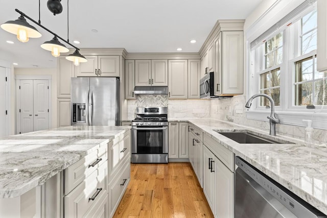 kitchen featuring sink, hanging light fixtures, light wood-type flooring, tasteful backsplash, and stainless steel appliances