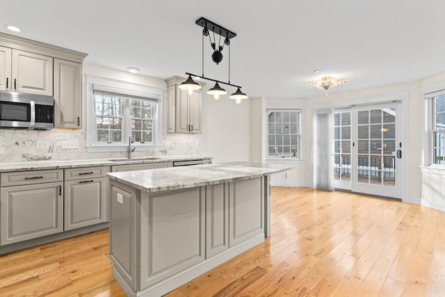 kitchen with sink, a center island, hanging light fixtures, backsplash, and gray cabinets