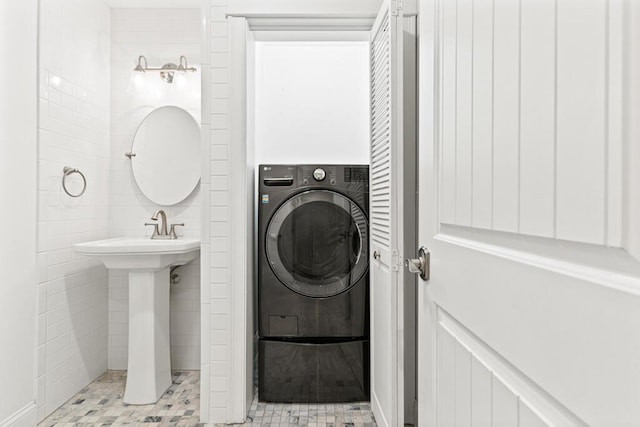 laundry room with washer / clothes dryer, light tile patterned floors, and tile walls