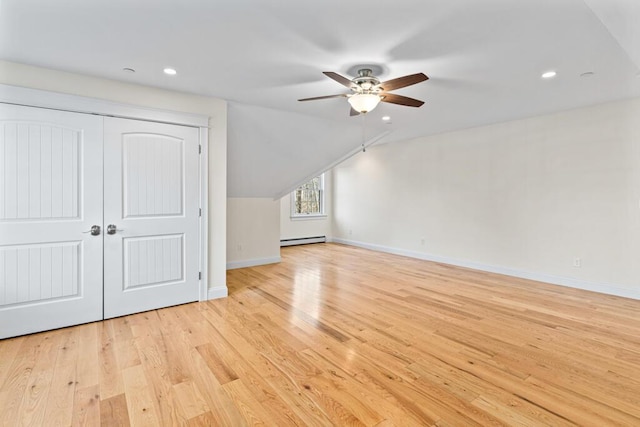 additional living space with lofted ceiling, light hardwood / wood-style flooring, ceiling fan, and a baseboard heating unit