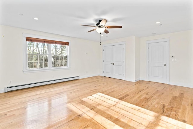 empty room with light wood-type flooring, a baseboard radiator, and ceiling fan