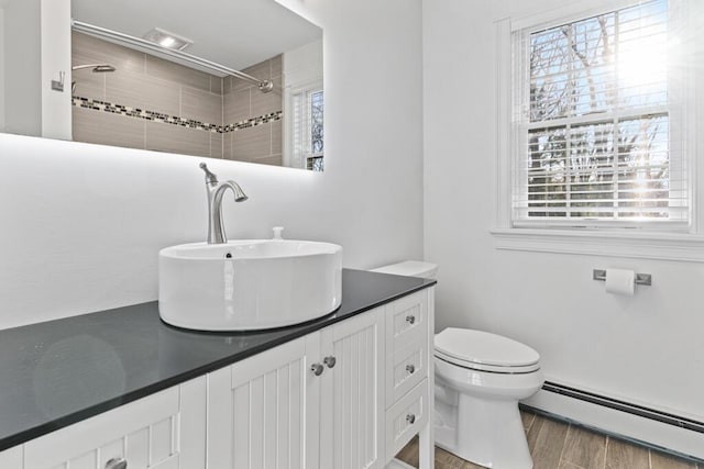 bathroom featuring vanity, a healthy amount of sunlight, toilet, and baseboard heating