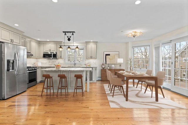 kitchen with appliances with stainless steel finishes, backsplash, light stone counters, decorative light fixtures, and a center island