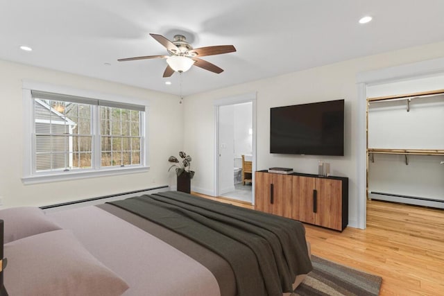 bedroom featuring baseboard heating, ceiling fan, a closet, and light wood-type flooring