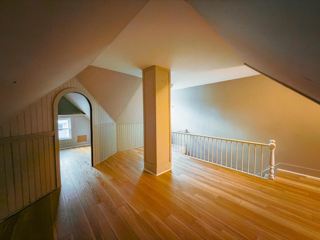 additional living space with hardwood / wood-style flooring and vaulted ceiling