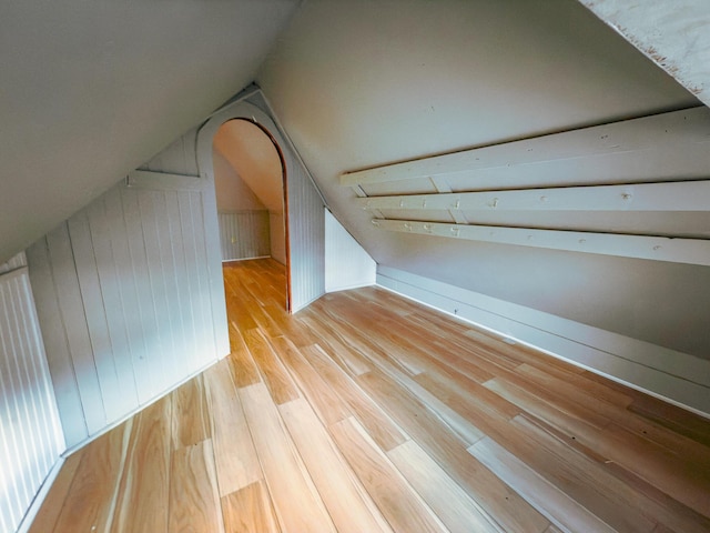 bonus room with wooden walls, light hardwood / wood-style flooring, and lofted ceiling