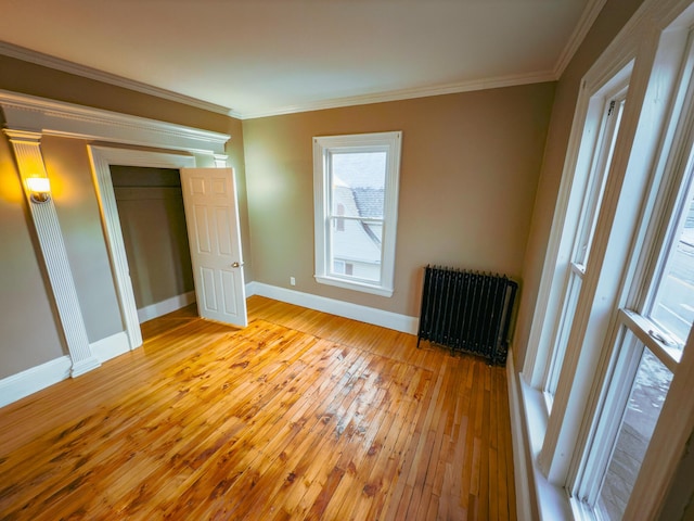 unfurnished bedroom with a closet, radiator heating unit, light hardwood / wood-style floors, and ornamental molding