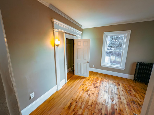 unfurnished bedroom with light wood-type flooring, radiator, and ornamental molding