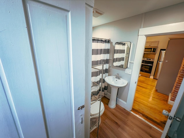 bathroom with wood-type flooring, toilet, and walk in shower