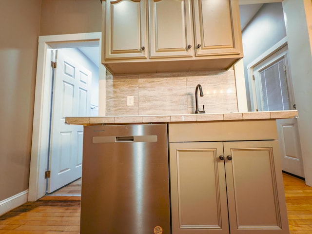 kitchen featuring cream cabinets, backsplash, light hardwood / wood-style flooring, and stainless steel dishwasher