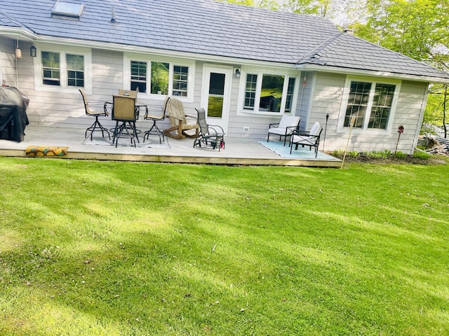 back of property with a yard and a wooden deck