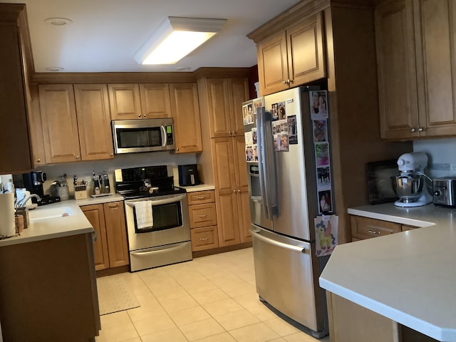 kitchen featuring kitchen peninsula, sink, light tile patterned floors, and stainless steel appliances