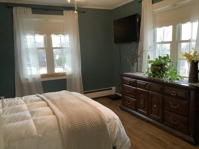 bedroom with dark wood-type flooring, crown molding, and a baseboard heating unit