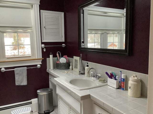 bathroom featuring decorative backsplash, vanity, and a baseboard heating unit