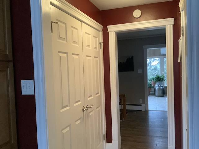 corridor featuring wood-type flooring and a baseboard heating unit