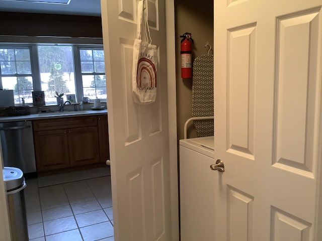 clothes washing area featuring washer / clothes dryer, sink, and light tile patterned flooring