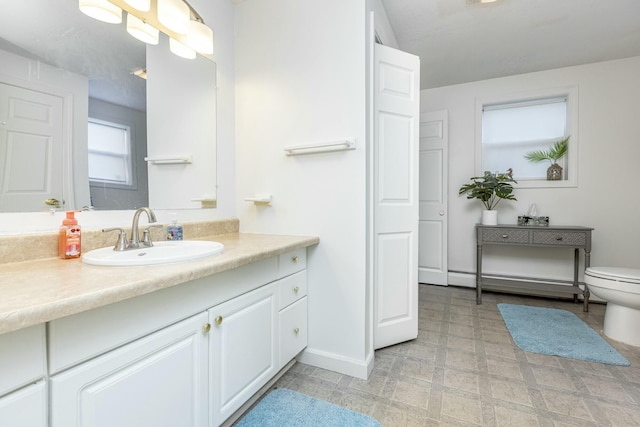 bathroom with vanity, toilet, and a baseboard heating unit