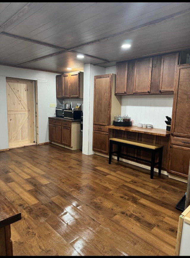 kitchen featuring recessed lighting, dark brown cabinets, dark wood-style floors, stainless steel microwave, and dark countertops