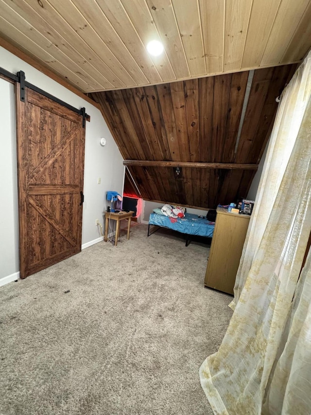 unfurnished bedroom with lofted ceiling, a barn door, carpet flooring, wooden ceiling, and baseboards