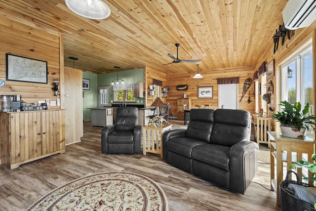 living room with a wall mounted air conditioner, a wealth of natural light, ceiling fan, and wooden walls