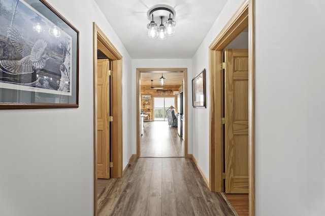 hall with wood-type flooring and a chandelier