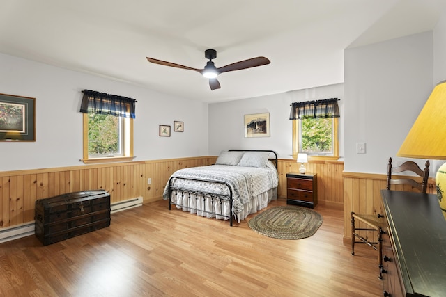 bedroom featuring hardwood / wood-style floors, a baseboard radiator, ceiling fan, and wooden walls