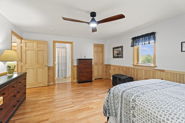 bedroom with light wood-type flooring, ceiling fan, and wood walls