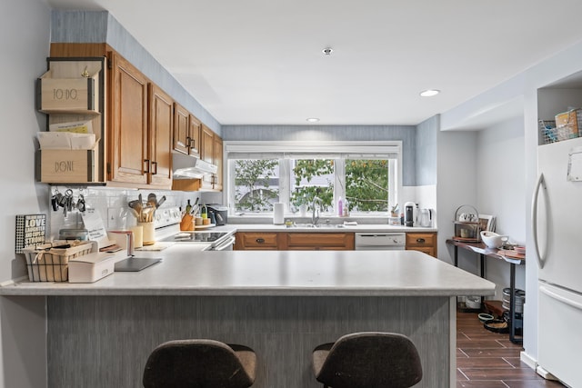 kitchen featuring kitchen peninsula, white appliances, and sink